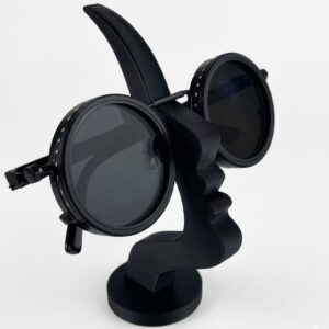Impoluxe abstract face sculpture display stand showcasing round designer sunglasses on a modern studio table.